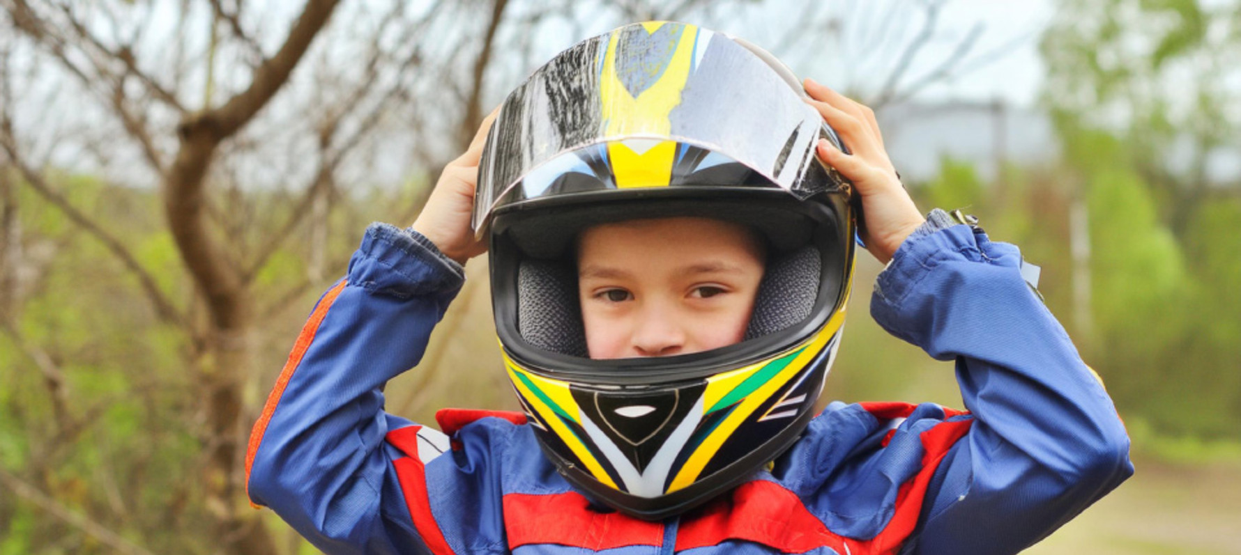 Child placing helmet on their head whilst looking towards the camera.