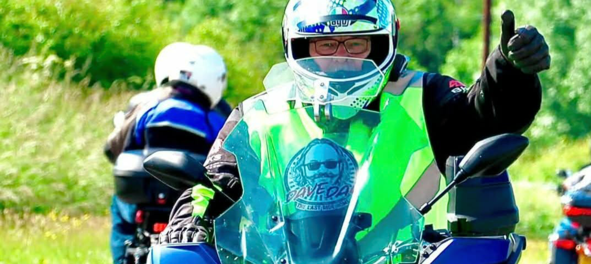 Rider at Dave Day with sticker in front windscreen with thumbs up at camera.