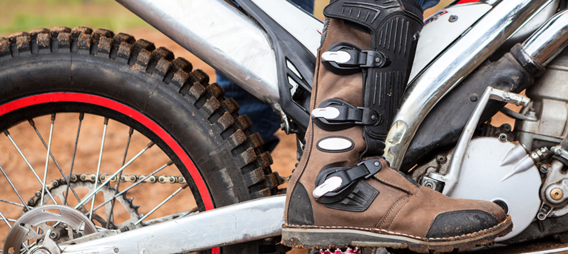 Close up of motocross boot whilst stood on motorbike.
