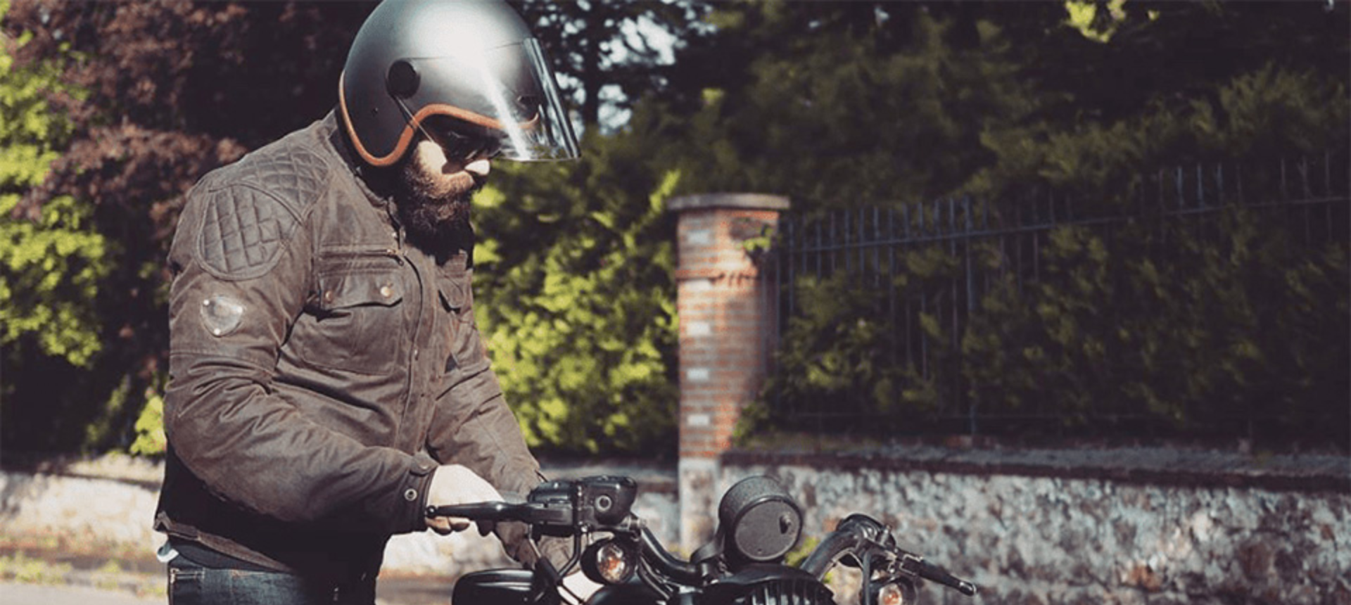 Man stood next to motorbike wearing motorcycle gear.