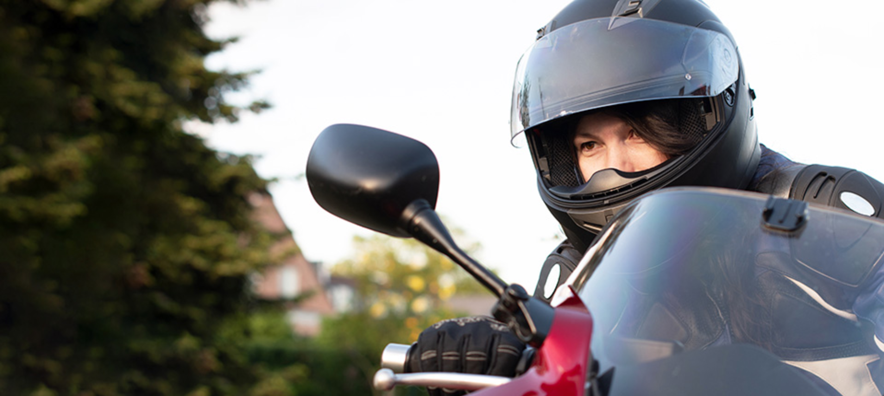 Person riding motorcycle with full face helmet looking through their mirror.