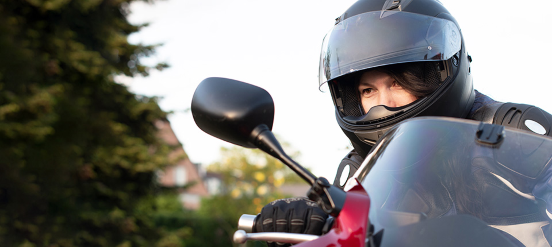 Person riding motorcycle with full face helmet looking through their mirror.