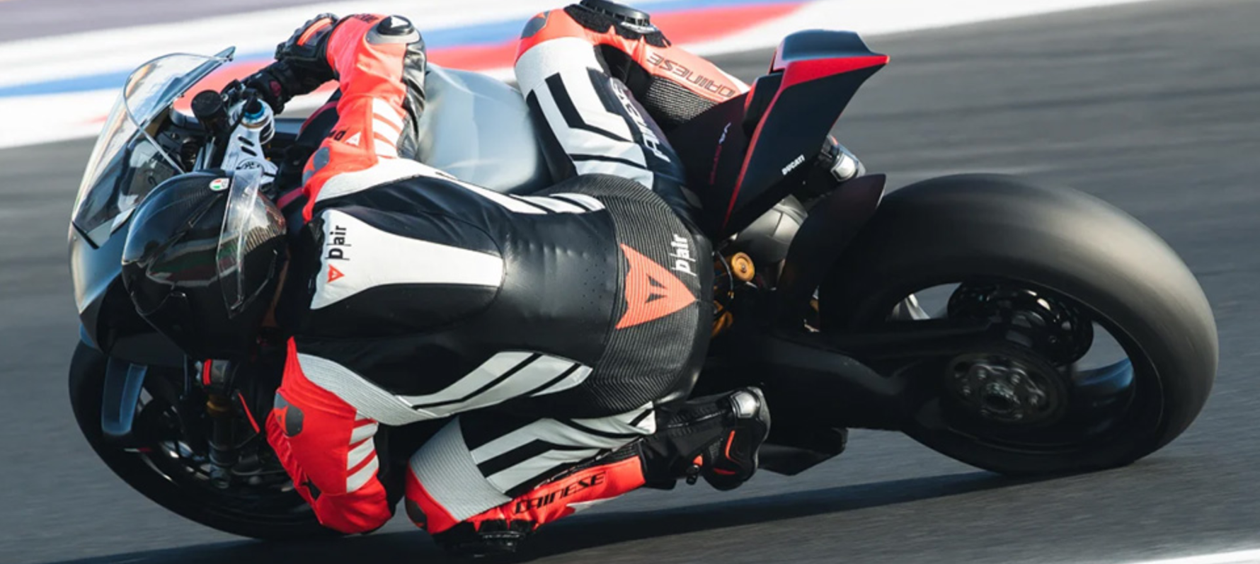 Moto GP rider leant over racing with back of leather suit visible.