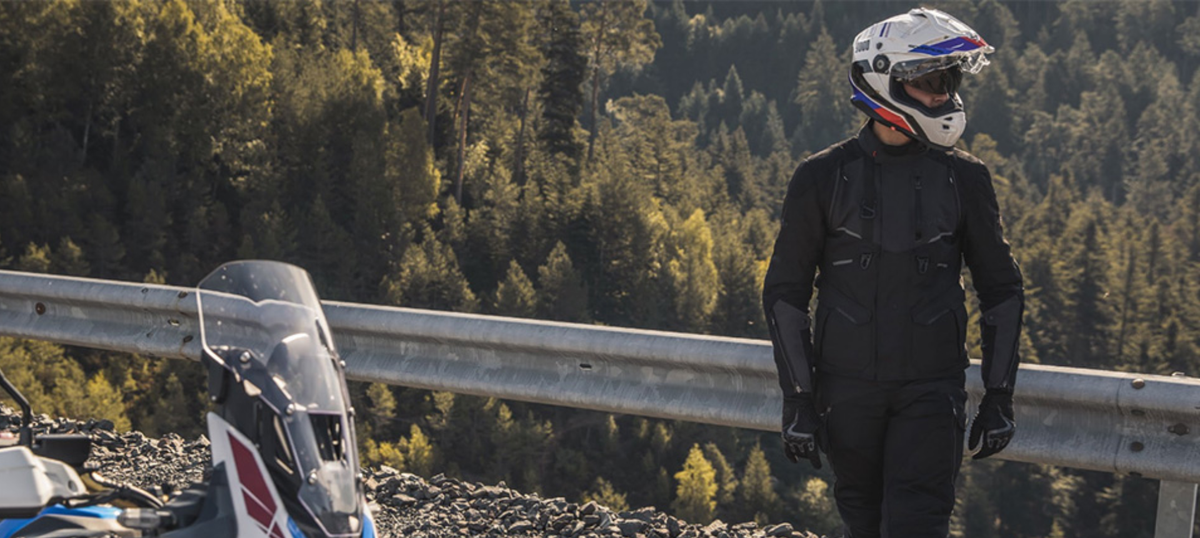 Rider wearing a Scorpion ADF-9000 adventure motorcycle helmet beside a motorcycle