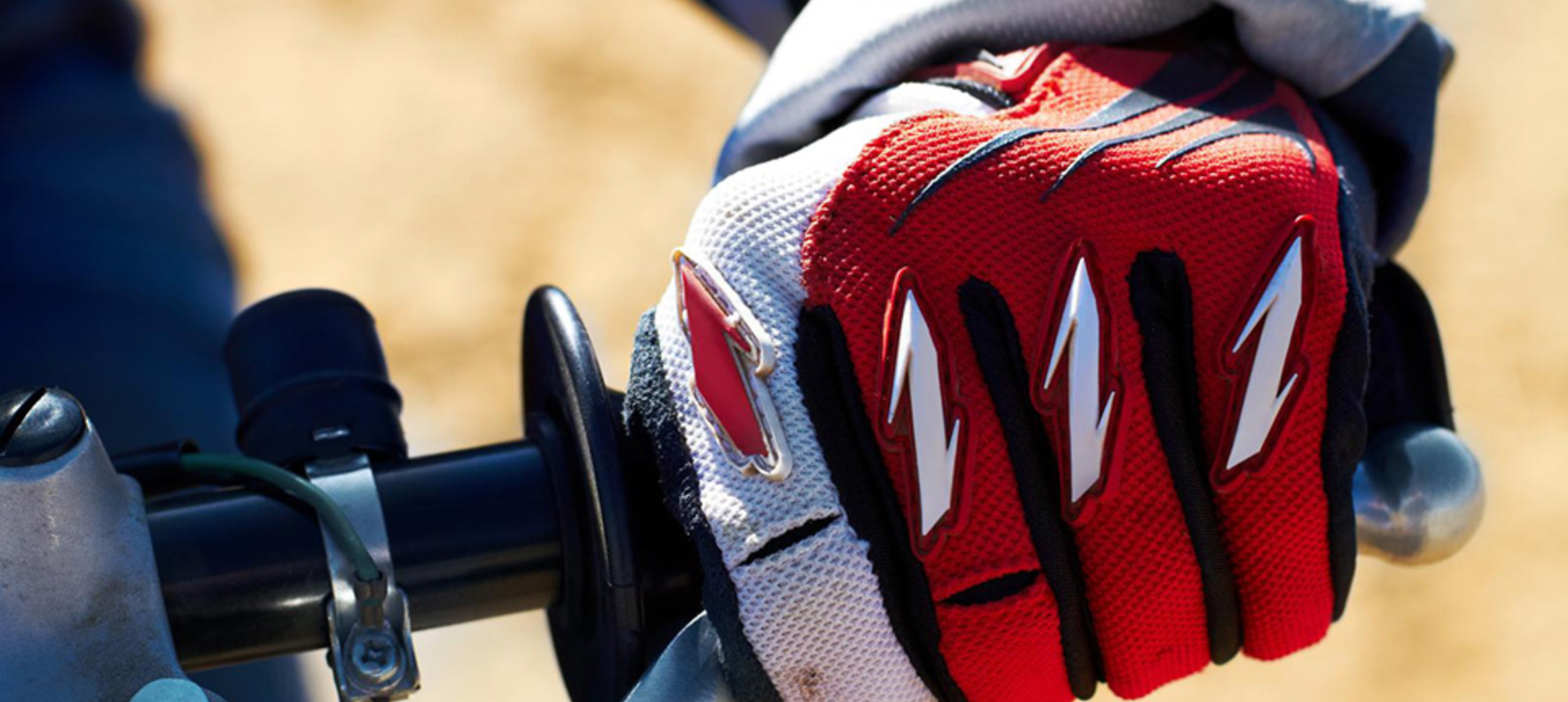Close up of person holding handlebars wearing motocross gloves.