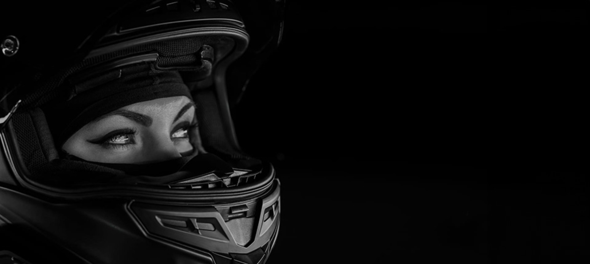 Black and white image of woman wearing motorcycle helmet.