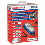 Optimate 3 12V 0.8A 7 Steps battery charger in its retail packaging, featuring a red box with blue and white text and graphics of the blue battery charger and red clamps.
