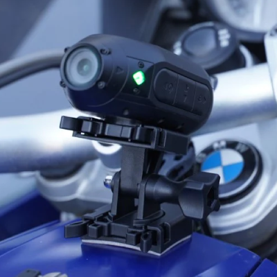 Action camera attached to mount on motorcycle tank.