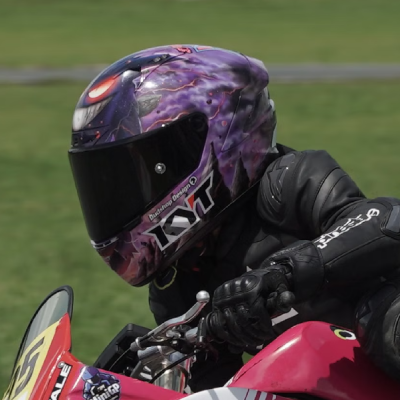 Child racing motorbike wearing junior motorcycle helmet.