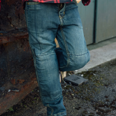 Child stood against wall wearing motorcycle jean trousers.