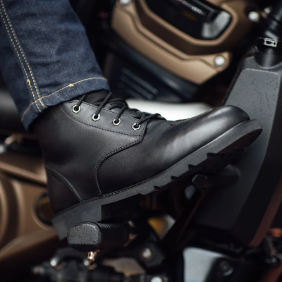 Close up of woman wearing motorcycle boots sat on bike.
