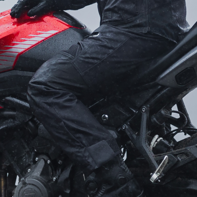 Close up of woman wearing motorcycle trousers on bike in rain.