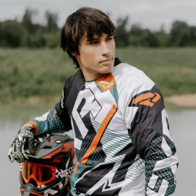 Man stood next to motocross wearing motocross shirt.