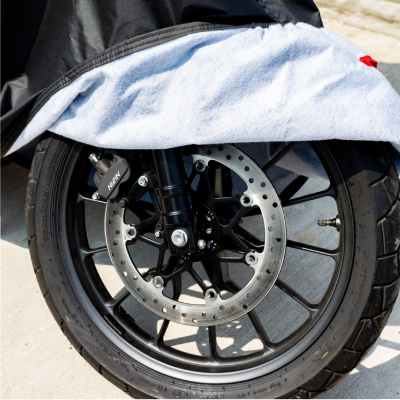 Motorcycle rain cover being put over motorbike.
