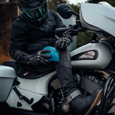 Rider sat on motorcycle applying padding to their trousers.