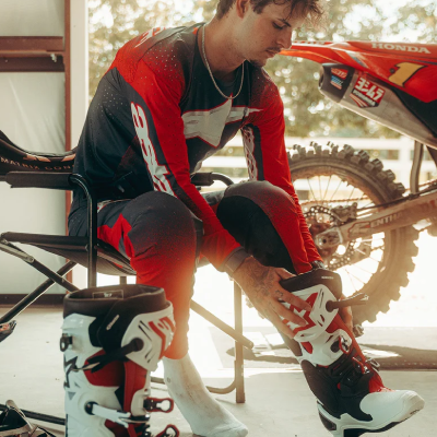 Man sat in chair putting on sports boots.