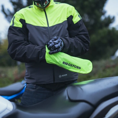 Motorcyclist putting on waterproof clothing in rain.